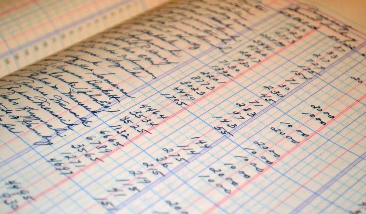An open paper ledger with handwritten columns and a pencil