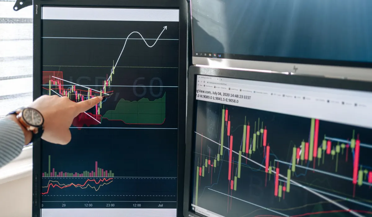 Two monitors showing candlestick charts in a dim room